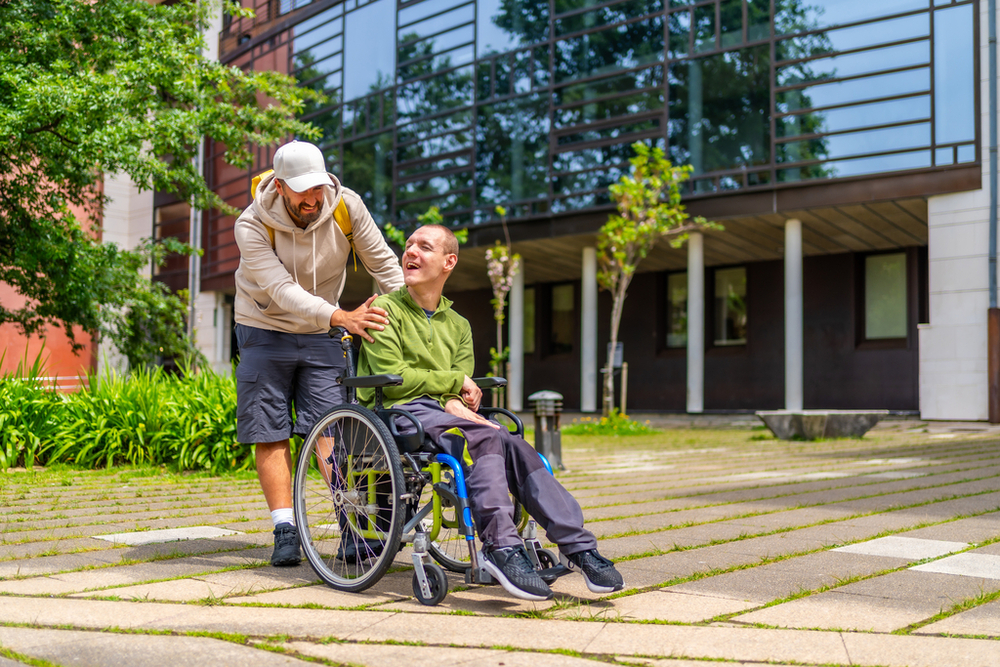 A man with special needs and his friend walking around a university campus.